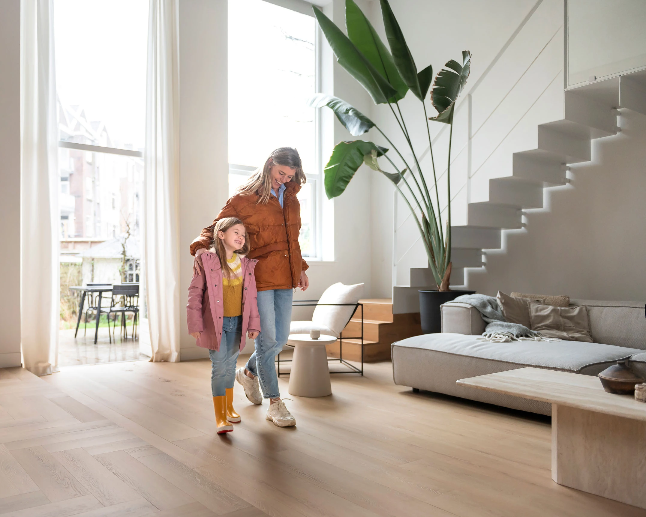 Moteris ir mergaitė eina per svetainę su batais, kurioje išklota Hebeta 54821 vinilinė danga